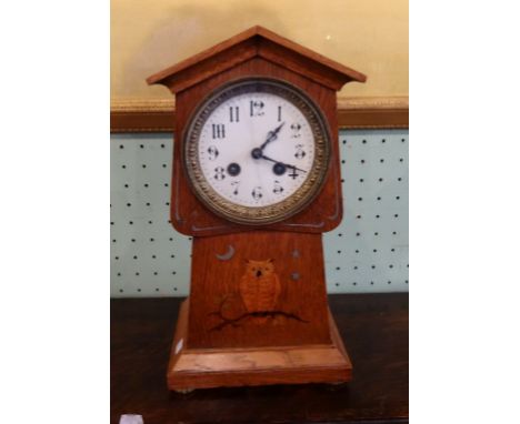 An early 20th century oak Arts &amp; Crafts mantel clock of Art Nouveau form, having inlaid owl decoration beneath a circular