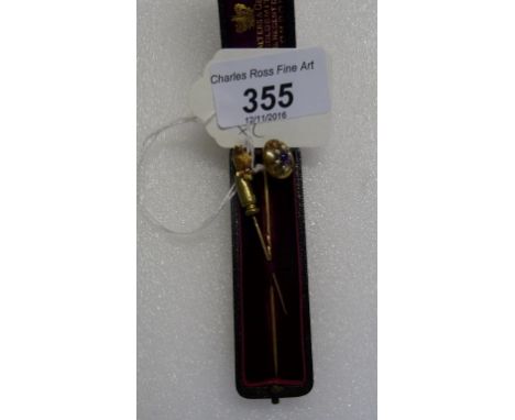 A Victorian yellow metal stickpin, set with an owl finial, together with a further yellow metal stickpin.