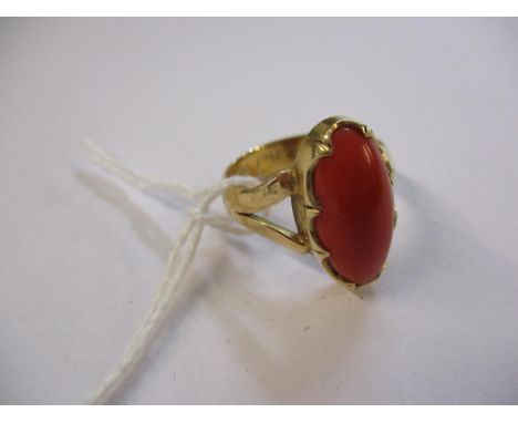 A yellow metal ring with central orange/red stone 