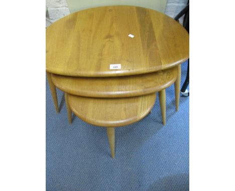 An Ercol light elm nest of three pebble tables 