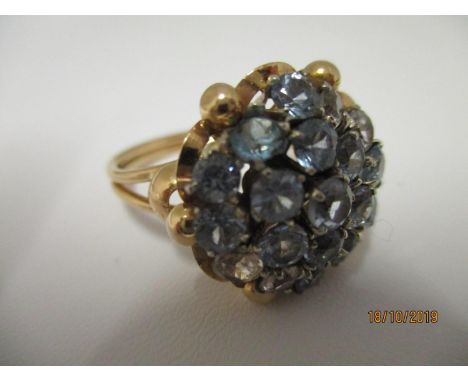 A blue and white synthetic spinal cluster ring, claw set, with a yellow mount to a double wire shank, stamped 750, total weig