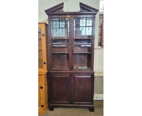 Victorian mahogany cupboard bookcase with twin bevel edged glass doors, fielded panel lower doors and broken arch pediment.  
