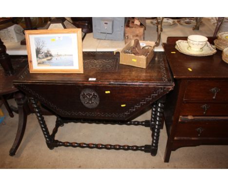 A carved oak gate leg table raised on barley twist supports 