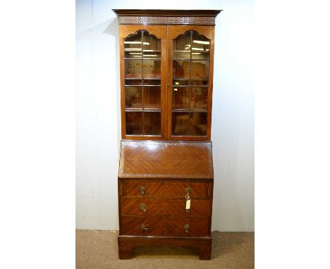 A 20th Century mahogany bookcase, the projecting cornice with blind fret carved frieze, above a pair of glazed astragal glaze