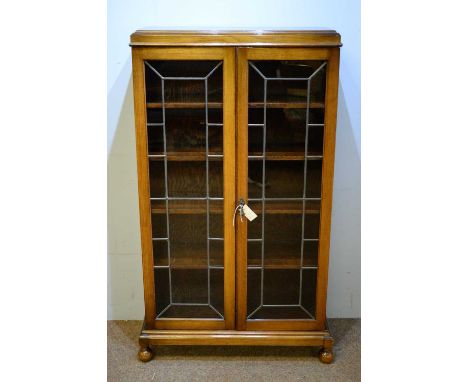 A 20th Century oak bookcase, the caddy top above a pair of glazed doors, enclosing five shelves, raised on bun feet, 139 x 77