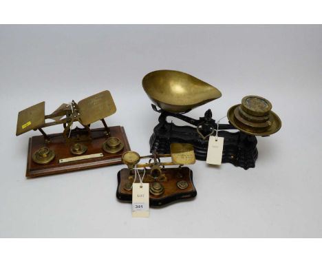 Two sets of brass postal scales on polished mahogany bases; a small set of brass and iron pan scales; and three weights.