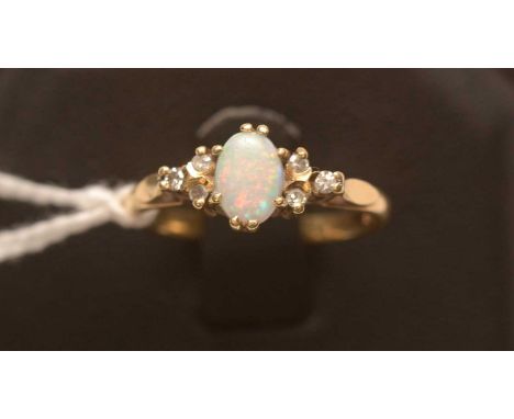 An opal and diamond ring, the oval opal cabochon flanked by six diamonds to shoulders, on 18ct. yellow gold shank, ring size 