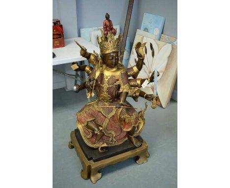 A large reproduction Asian figure of a female deity, wearing an elaborate crown headdress with diminutive figure, raised on a
