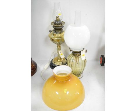 A brass oil lamp, with reproduction shade, corinthian column base on circular black glass stand; an amber glass oil lamp with