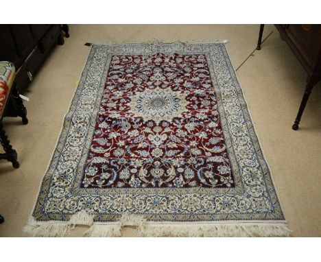 A modern Isfahan carpet, the abrashed madder ground with central ivory medallion contained within a border of repeating folia