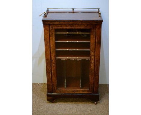 A Victorian walnut music cabinet, the rectangular top with three-quarter brass gallery, above a glazed cupboard door, enclosi