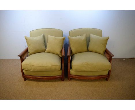 A pair of Ercol teak Bergere chairs, the rectangular backs with cane sides above cushion seats, raised on circular bun feet.