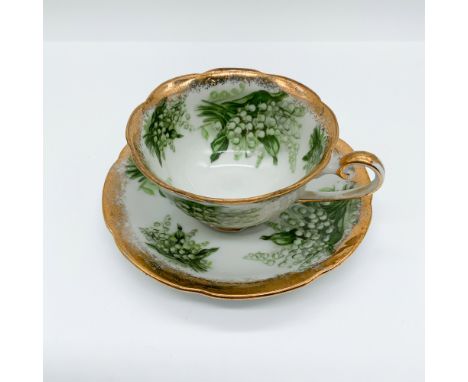 Exquisite porcelain teacup and saucer set featuring a delicate lily of the valley motif accented with rich gilt trim. The sca