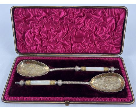 A pair of late Victorian silver plated serving spoons with gilt bowls and mother of pearl handles. Decorative scroll and foli
