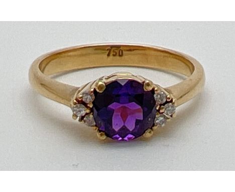 An 18ct gold amethyst and diamond dress ring. A central round cut .75ct amethyst with 3 small round cut diamonds to each side