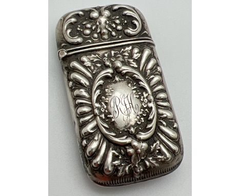 A Victorian silver vesta case with decorative floral and scroll detail shown in relief. Hinged lid, stamped 'sterling' to inn