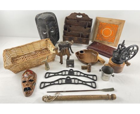 A box of assorted vintage wooden and metal items. To include: grinder, letter rack, carved animals and ethnic masks. 