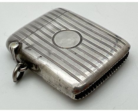 An art Deco silver vesta case with engine turned decoration and circular empty cartouche to front. Striker to base with hangi