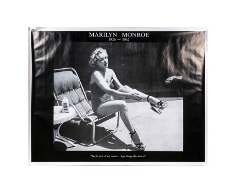 Large black and white poster print with semi-gloss finish; white text on black border. Features Marilyn Monroe seated on a be