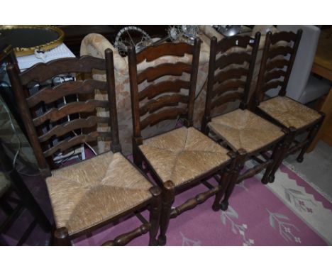 A set of four traditional oak ladder back chairs having rush seats