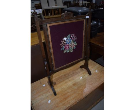 An early 20th Century oak firescreen having woolwork panel