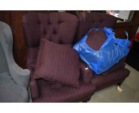 A pair of modern button back armchairs in burgundy upholstery, with additional cushions