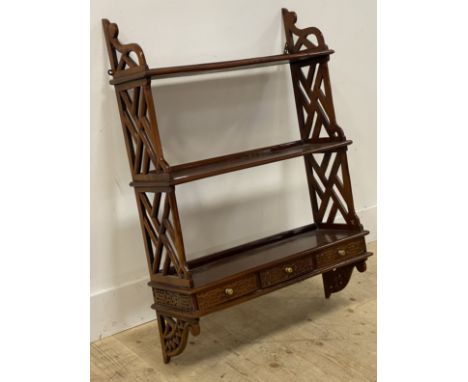 A reproduction mahogany wall rack in the Chippendale taste, with lattice pierce carved panel end supports and three blind fre