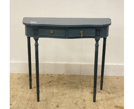 A traditional blue painted console table of serpentine outline, fitted with two drawers and raised on turned, fluted, and tap