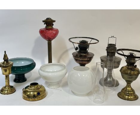 A collection of various oil lamp bases comprising, one tall brass Corinthian style with cranberry glass to body (h-48cm), a A