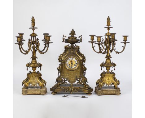 A three-piece brass clock set in Louis XV style, consisting of a pendulum and two candlesticks, each with five lightsEen drie