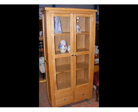 A modern light oak bookcase enclosed by glazed doors - width 90cm 