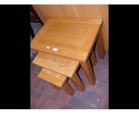 A nest of three light oak occasional tables 