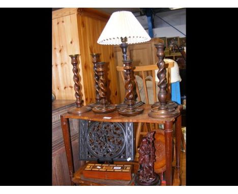 Six oak barley twist candlesticks together with a table lamp and carved Chinese figure - on two shelves