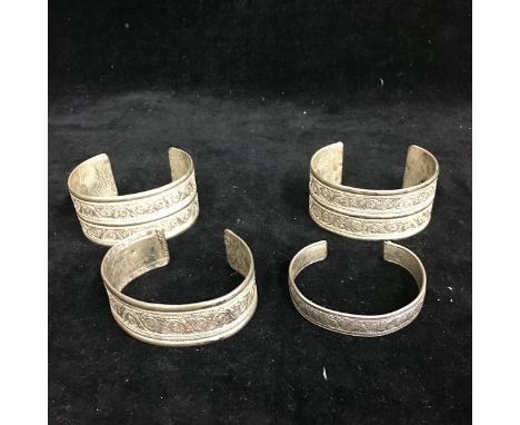 Four Chinese white metal filigree cuff bangles, decorated with 's' scroll filigreework bands to the exterior the interior wit