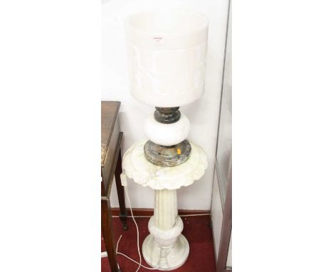 An alabaster table lamp, having a cylindrical shade incised with flowers, on a marble column, compressed circular base and fu