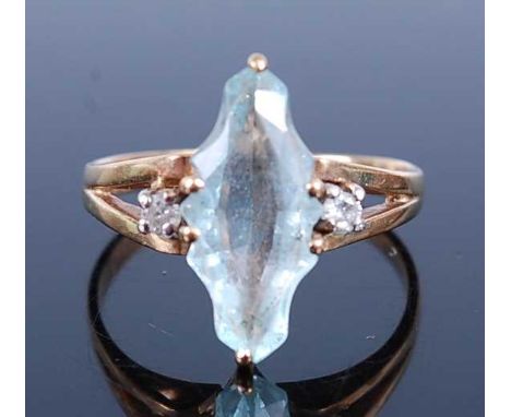 A 9ct yellow gold, aquamarine and diamond dress ring, comprising a marquise shaped aquamarine with scalloped sides flanked on