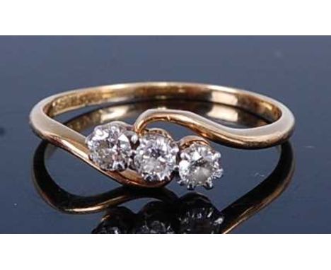 A yellow and white metal diamond crossover trilogy ring, comprising round brilliant cut diamond in claw settings, diamond dim