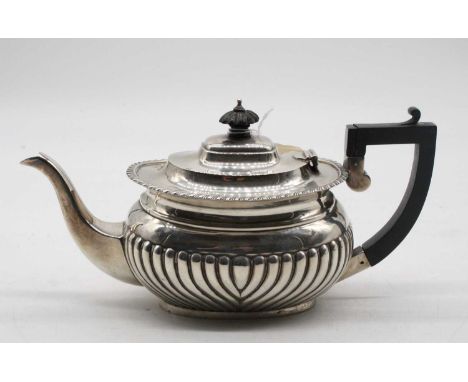 A late Victorian silver teapot, of half-gadrooned oval form, having ebonised finial and angular handle, makers mark rubbed, C