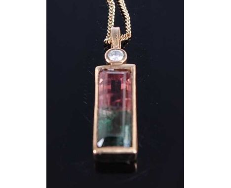 A yellow metal parti-coloured tourmaline and diamond pendant, the rectangular green/pink tourmaline in a bezel setting with a