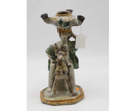 A 19th century continental glazed pottery oil lamp, having three receptacles surmounted upon the head of a figure on the back