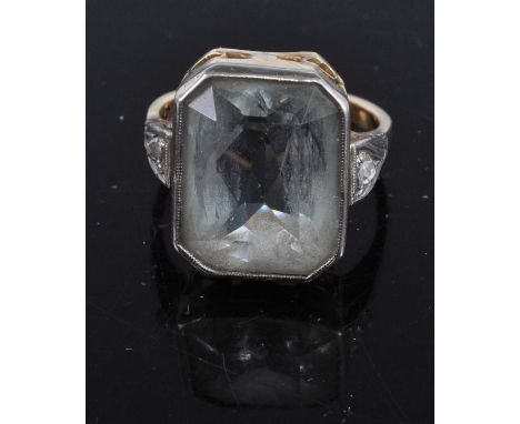 An Art Deco yellow metal and aquamarine(?) dress ring, the octagonal cut aquamarine being of washed-out colour and measuring 