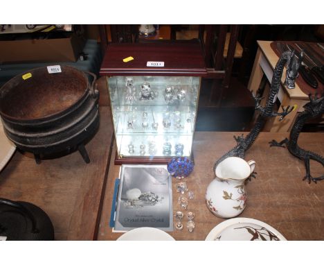 A display case and a collection of various Swarovski and other glass ornaments together with a paperweight