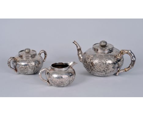 A Chinese silver three piece Tea Service decorated insects and chrysanthemum, the teapot and sucrier with flower finials, mar