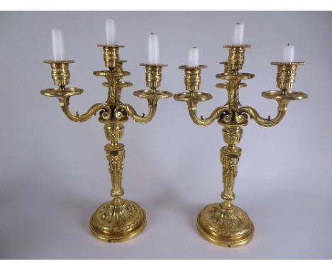 A pair of gilt metal three branch, four light Candelabra with beaded rims, lion mask and swag decorated fluted tapering colum