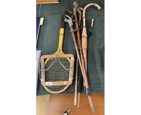 Collection of walking sticks together with a tennis racket and shooting stick 