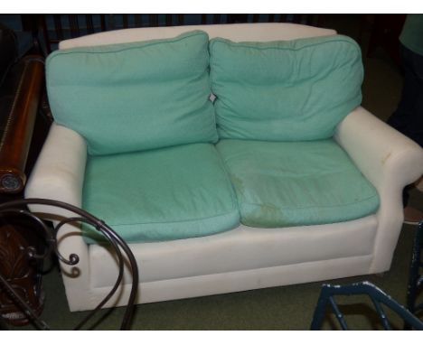 Small cream two seater sofa with removable green covers and feather cushions