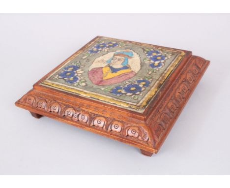 AN EARLY ISLAMIC SQUARE POTTERY TILE painted with a portrait and signed, 19cm square in a wooden stand.