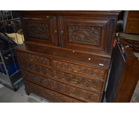 A 19th Century oak cabinet on two over three drawers, in the Continental style having carved panel decoration, brass handles 