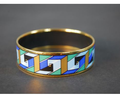 Hermès, a gold plated and enamel blue, green and gold geometric swirl design bangle, makers mark to interior. Diam.6.5cm 