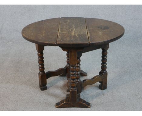 An early 20th century oak Sutherland table, the circular top with two drop leaves, on bobbin turned legs joined by curved str